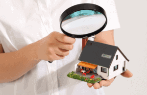 A person holding a magnifying glass over a house.